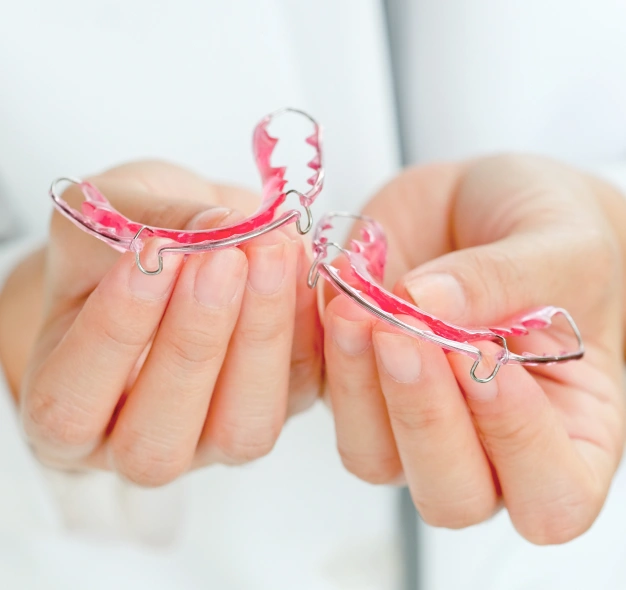 Clear orthodontic retainers held in hands